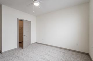 Empty carpeted room with open door and ceiling fan at Allure Apartments, Indiana, 46184