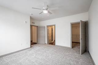 Carpeted bedroom with ceiling fan and multiple doorways at Allure Apartments, Whiteland, IN