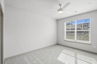 A room with a ceiling fan and a window with blinds.