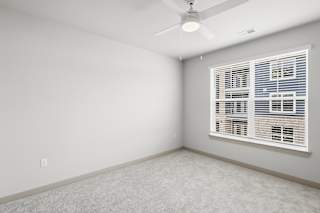 A room with a ceiling fan and a window with blinds.