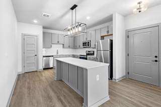A modern kitchen with a white island and stainless steel appliances. at Arbour Place Apartments, Jeffersonville, Indiana