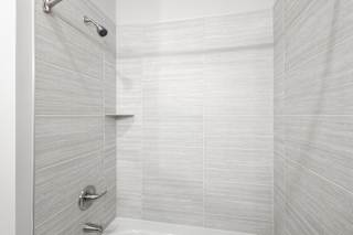 A white tiled shower with a silver faucet at Arbour Place Apartments, Indiana, 47130