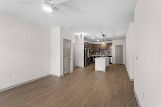 A spacious room with wooden floors and a kitchen area in the background.at Arlington Farms, Greenwood, IN, 46143