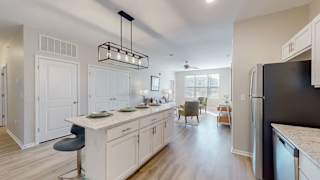 A modern kitchen with white cabinets and a black fridge at The Slate, Jeffersonville, 47130
