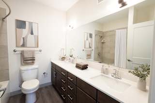 A bathroom with a toilet, sink, and mirror.