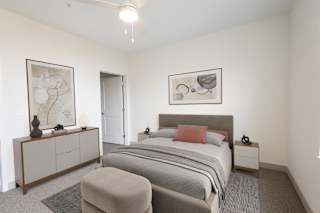 A bedroom with a bed, nightstand, and a cabinet with a vase on top.