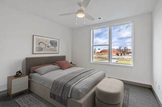 A bedroom with a bed, nightstand, and window.
