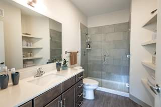 A modern bathroom with a walk-in shower and a white sink.