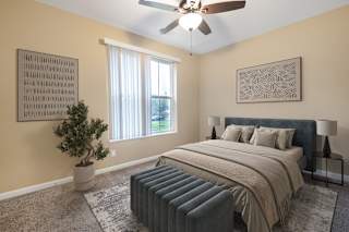 A bedroom with a bed, a ceiling fan, and a potted plant.