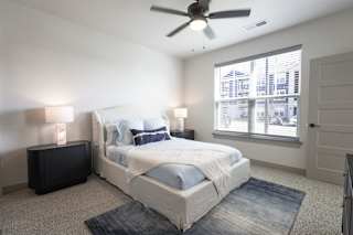 A bedroom with a large bed and a ceiling fan.