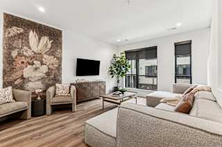 A living room with a large tapestry on the wall and a couch with a pillow on it.