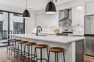 A modern kitchen with white countertops and stainless steel appliances.