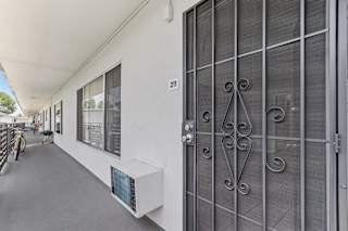 A white building with a glass door and a number 211 on the wall.