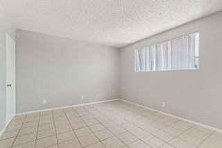A room with a tiled floor and a window with blinds.
