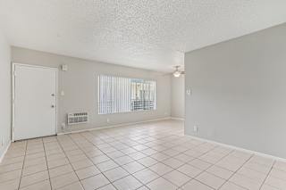 A spacious room with a white door and a window with blinds.