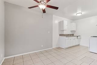 A room with a ceiling fan and a kitchenette.