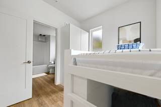 A white bedroom with a bed and a mirror.