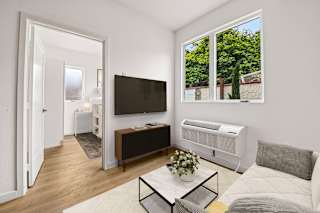 A living room with a white sofa, a black TV, and a glass coffee table.
