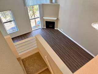 A living room with a fireplace and a staircase leading to the upper floor.