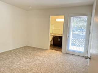A room with a carpeted floor and a door leading to a balcony.