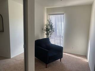 a living room with a black chair and a window