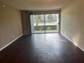 an empty living room with wood floors and a sliding glass door