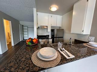 A kitchen with a granite countertop and a bowl of fruit on it.