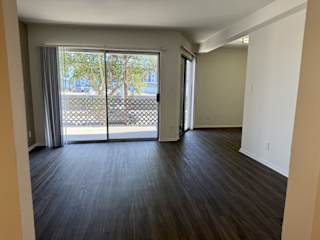 A room with wooden floors and sliding glass doors leading to a balcony.