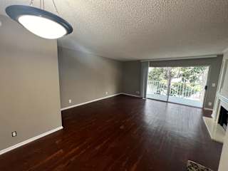 an empty living room with wood floors and a sliding glass door