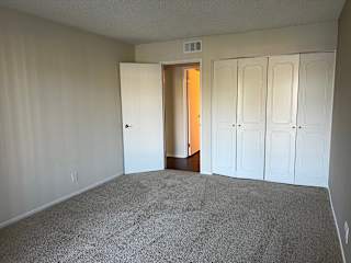 an empty bedroom with white closets and carpeting