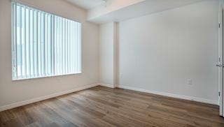 A room with wooden flooring and a window with blinds.