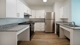 A kitchen with a refrigerator, sink, and cabinets.