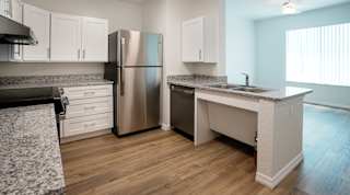 A kitchen with a stainless steel refrigerator, sink, and cabinets.