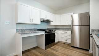 A kitchen with a stainless steel refrigerator and a granite countertop.