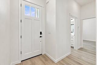 A white door with a black handle is in a room with white walls and wooden flooring.