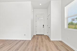 A white hallway with wood flooring and a white door.