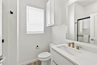 A white bathroom with a toilet, sink, and mirror.