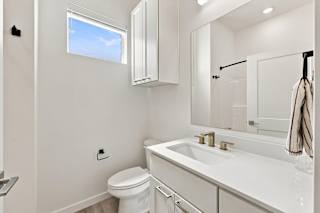 A white bathroom with a toilet, sink, and mirror.
