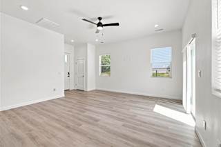 A spacious room with a ceiling fan and lighting fixtures.