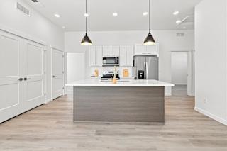 A modern kitchen with a central island and pendant lights.