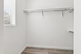 A white wall with a wooden floor and a white shelf.