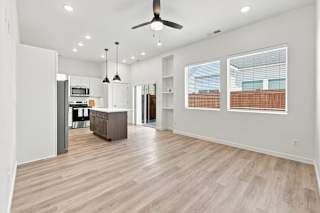 A spacious living room with a kitchen in the background.