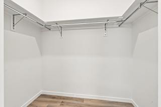 A white wall with a wooden floor and a metal pipe running along the top.