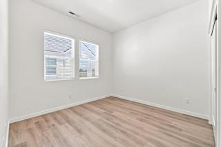 A room with wooden flooring and two windows.