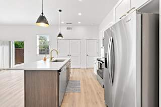 A modern kitchen with a large refrigerator and wooden cabinets.