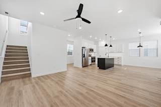Spacious kitchen and living room with wooden flooring and a staircase at Alante Homes at Spring Run, Caldwell, 83607