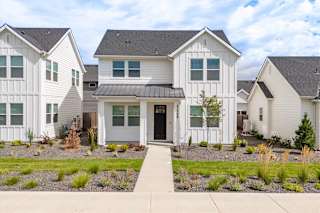 A white house with a black roof and a grey front door. at Alante Homes at Spring Run, Idaho, 83607