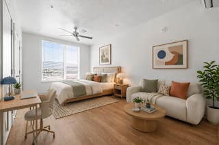 A modern bedroom with a large bed, a couch, a desk, and a ceiling fan.
