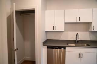 A kitchen with white cabinets and a stainless steel dishwasher.