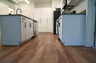 A kitchen with white cabinets and a wooden floor.